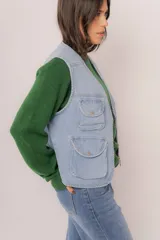 Chaleco de jean celeste con múltiples bolsillos frontales con botón y cierre frontal con cremallera.
