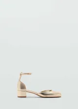 Zapato de tacón bloque color dorado, con punta redonda, efecto charol y cierre de tira con hebilla.