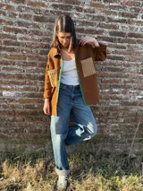 Camisa marrón con cuello, cierre frontal con botones, dos bolsillos frontales y detalles de lentejuelas.