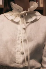 Camisa blanca de lino con cuello con volados, mangas largas abullonadas y botones forrados.