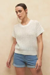 Chaleco tejido color beige con diseño calado, cuello redondo y mangas cortas.