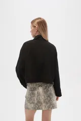 Campera color beige de manga larga, con cuello alto, cierre frontal con cremallera y botones a presión, bolsillos con solapa en el pecho y puños con trabilla ajustable.