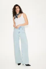 Pantalón jean de tiro bajo en denim bouclé celeste, de algodón rígido, con cinco bolsillos, cierre con botón y corte holgado con piernas amplias.