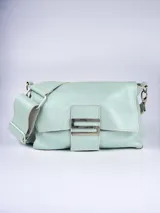 Bandolera de cuero color celeste pastel, con correa ancha ajustable y hebilla metálica plateada.