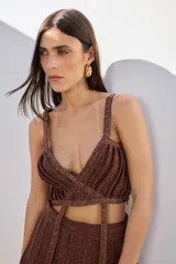 Top negro con lurex, de breteles finos y corte irregular con tiras cruzadas en el abdomen.