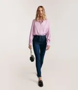 Pantalón de jean skinny azul oscuro, con cintura alta, trabillas, bolsillos delanteros y traseros, y cierre frontal con botones forrados.