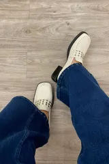 Mocasín de cuero marfil con detalle de tachas en la capellada y tacón de 3,5 cm.
