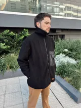 Campera de hombre color crema, de textura peluda, con cierre frontal, cuello alto, bolsillos laterales y un bolsillo impermeable negro en el pecho.