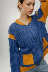 Chaqueta estilo bomber tejida color marrón con detalles en beige, cierre frontal y bolsillos delanteros.