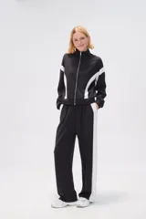 Campera deportiva negra con cierre frontal, cuello alto y detalles de recortes curvos blancos en mangas y laterales.