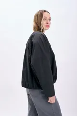 Campera negra corta con frunces en la cintura y cierre frontal.