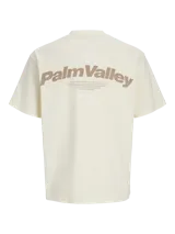 Remera color crema de corte oversize con cuello redondo y mangas cortas. Estampado en la espalda con la frase "Palm Valley" en color marrón.