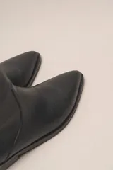 Bota corta de cuero vacuno color negro, con punta fina y taco bajo.