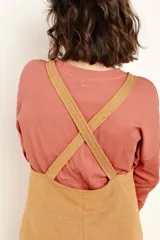 Vestido jumper color ocre, de corte recto, con breteles anchos y bolsillos frontales.