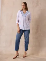 Blusa blanca de poliéster y rayón con escote en V bordado y mangas tres cuartos regulables con presilla y botón.