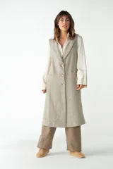 Chaleco largo color beige con solapas, cierre frontal con botones y bolsillos ojal. Confeccionado en lana fina sin teñir.