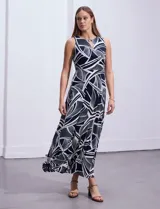Vestido largo de seda fría con estampado abstracto en blanco y azul marino. Tiene cuello a la base cruzado con abertura ojal y aplique metálico.