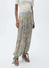 Pantalón largo de gasa con estampado floral en tonos verde, celeste y marrón. Diseño balloon con detalle de lazos en el bajo y tiro medio.