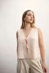 Chaleco amarillo pálido con escote en V y cierre frontal con lazos.