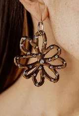 Aros colgantes con forma de flor de acrílico color marrón, con resina y strass salpicado. El arito es de acero quirúrgico.