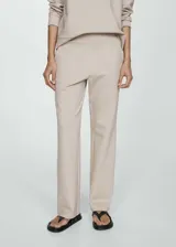 Pantalón de vestir color beige, de corte recto y tiro alto. Presenta cintura elastizada y bolsillos laterales.