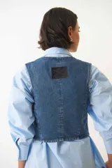 Chaleco denim con botones plateados en la parte delantera y bolsillos simulados.