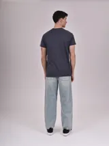 Remera gris oscuro con cuello redondo, mangas cortas con rayas blancas y amarillas en los hombros, y estampado frontal con la palabra "Brooklyn" y el número 77 en amarillo.