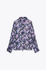 Camisa semitransparente de manga larga con estampado de flores color lila y cuello solapa. Presenta volantes en el frente y cierre con botones.