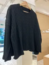 Sweater negro de tejido de punto trenzado, con cuello redondo y corte holgado.