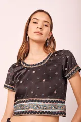 Top negro con bordados de flores y detalles de cuentas en el escote y mangas cortas.
