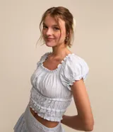 Blusa corta de tricolina a rayas celestes y blancas, con escote elástico, mangas cortas abullonadas con frufrú y fruncido en el bajo.