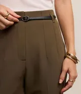 Pantalón de vestir azul marino, de corte zanahoria, con cinturón fino negro con hebilla dorada.