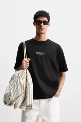 Camiseta negra de corte holgado con cuello redondo y mangas cortas. Estampado frontal con la frase "Unfolding Dreams" en letras blancas.