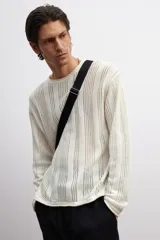 Buzo color crema en punto pointelle de mezcla de algodón, lino y viscosa. Modelo de hombros caídos con cuello redondo y bajo recto. Borde enrollado en cuello, puños y bajo.