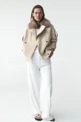 Cazadora color crudo con cuello solapa y cuello de pelo sintético desmontable, manga larga con trabillas y botones, bajo con elásticos y cierre cruzado con botones.