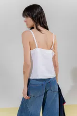 Top de lino color crudo con rayas verticales finas en negro, escote en V y breteles regulables con detalle de borlas.