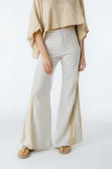 Pantalón acampanado color crema con finas rayas verticales marrones y paneles laterales color beige.