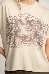 Remera color arena de algodón peinado con estampa frontal de texto con diseño floral.