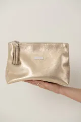 Sobre de cuero color dorado con cierre superior y detalle de borla en el tirador.