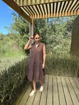 Vestido verde militar de lino, corte a la rodilla, sin mangas, con cuello mao y botones de nácar. Presenta varios cortes en su largo, aportando movimiento y un toque moderno a este diseño fresco y elegante.