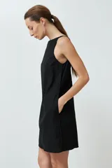 Vestido corto negro de lino, corte recto, sin mangas y con bolsillos laterales.