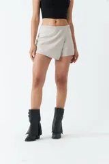 Short falda color gris claro de gamuza sintética, con corte asimétrico y cierre lateral invisible.