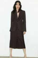 Blazer marrón de corte entallado, con solapas de pico, cierre de un botón, hombreras, bolsillos delanteros de parche, puños con abertura y botón, abertura trasera y forro interior.