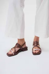 Sandalias bajas de cuero color marrón con tiras cruzadas y detalle de tira delgada color rosa.