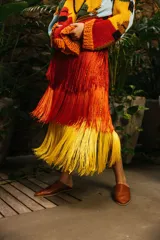 Pollera midi de crochet con tres capas de flecos en degradé de rojo a amarillo. Tiene cintura elástica y está confeccionada en hilado de seda.