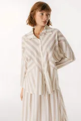 Camisa celeste y blanca a rayas verticales, de corte holgado y mangas largas.