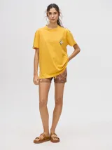 Remera amarilla de corte cuadrado y holgado, con estampado de estrella plateada con borde negro en el frente.