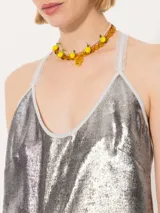 Top corto plateado con breteles finos y espalda descubierta con flecos cruzados.