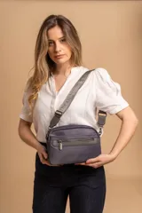 Bandolera color rosa viejo con detalles en cuero marrón claro, múltiples cremalleras metálicas y herrajes plateados. Incluye correa ancha ajustable con el logo de la marca.