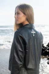 Campera estilo jeanera confeccionada en cuero ovino italiano, con broches metálicos y bordado de flor de lis en la parte superior de la espalda.